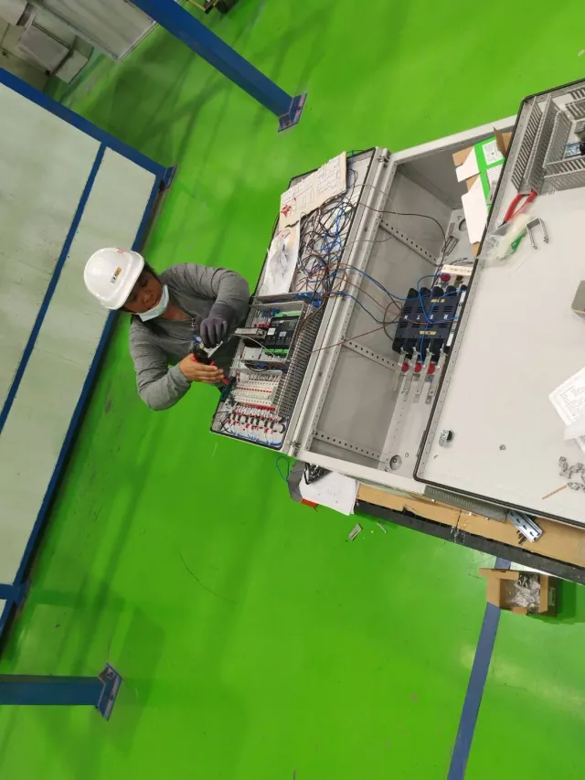Technician beside an open electrical cabinet
