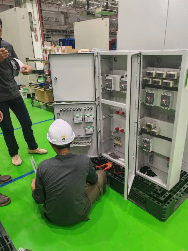 Technician inspecting an electrical cabinet on the workshop floor