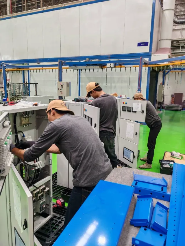 Technician working on electrical equipment beside workshop tools
