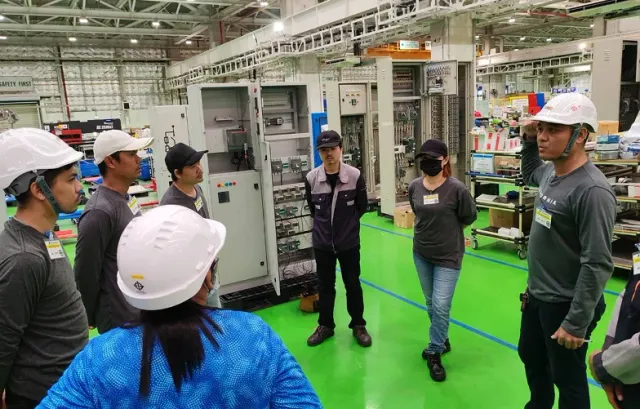 Engineering team reviewing a row of electrical cabinets
