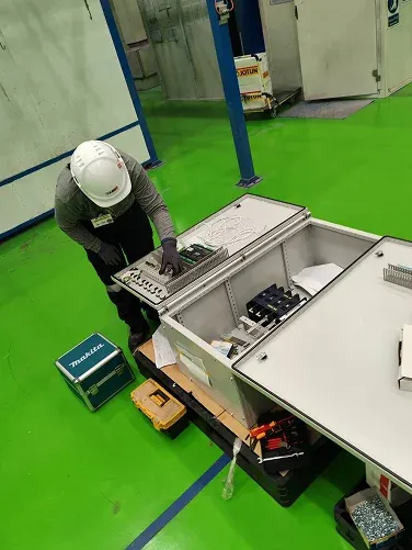 Technician inspecting an electrical cabinet laid on the workshop floor