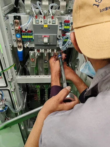 Technician working on wiring inside an electrical cabinet