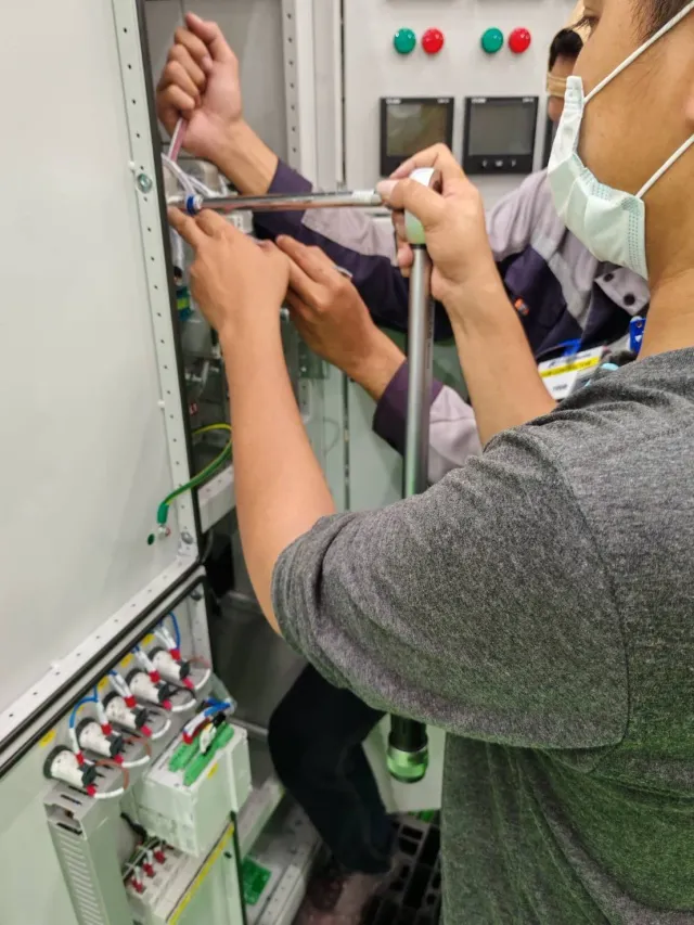 Technician servicing components inside an electrical cabinet